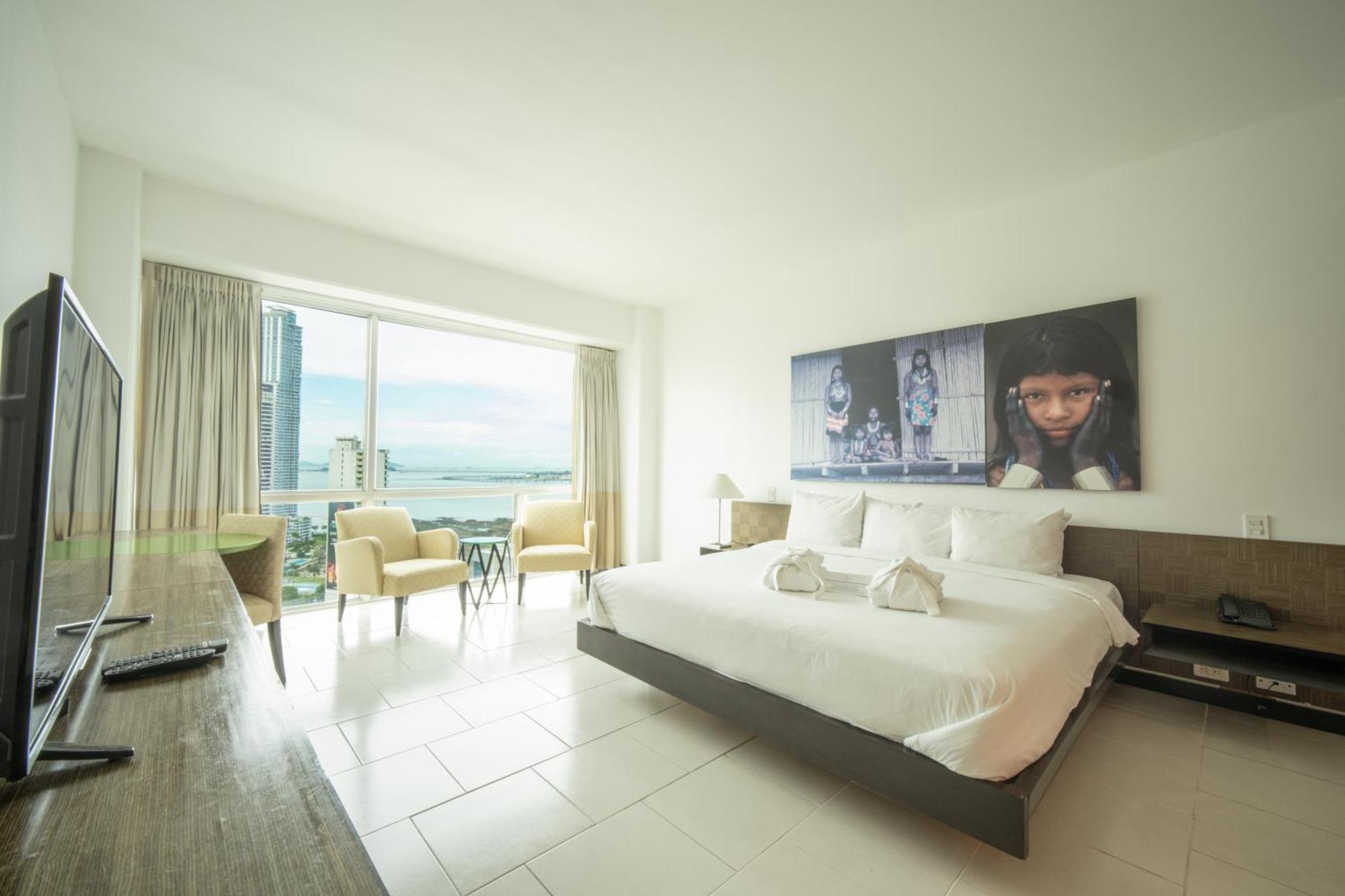 Decapolis Hotel ปานามาซิตี้ ภายนอก รูปภาพ The photo showcases a modern hotel room. It features a large bed with white linens and decorative towels arranged neatly. Behind the bed, there's a large artwork or photo displayed on the wall. The room has a large window that allows natural light to