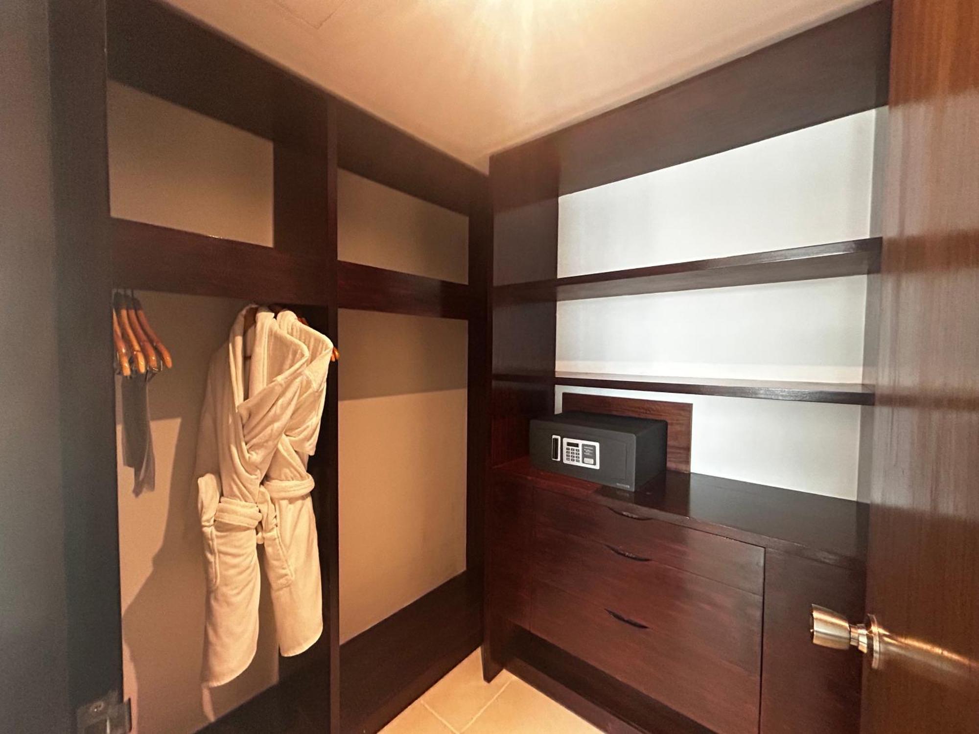 Decapolis Hotel ปานามาซิตี้ ภายนอก รูปภาพ The photo shows a closet or wardrobe space with modern design. Inside, there are several features: 

- On the left side, there are open shelves.
- A white bathrobe hangs on a hanger.
- There is a dark wooden cabinet or drawer section below the shelve