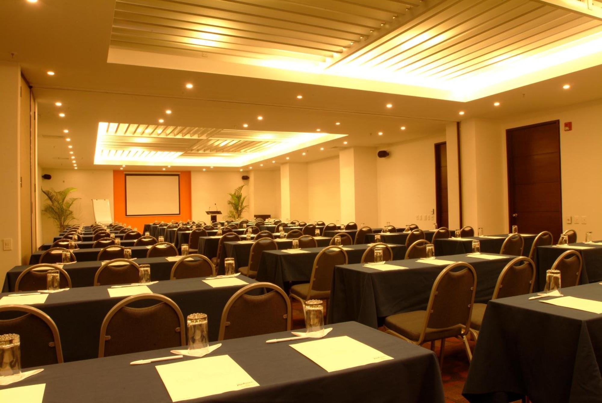 Decapolis Hotel ปานามาซิตี้ ภายนอก รูปภาพ The photo shows a conference or meeting room set up for an event. There are multiple rows of tables arranged with dark-colored tablecloths. Each table is equipped with a piece of paper or a notepad, and there are glass jars or cups placed on the tabl